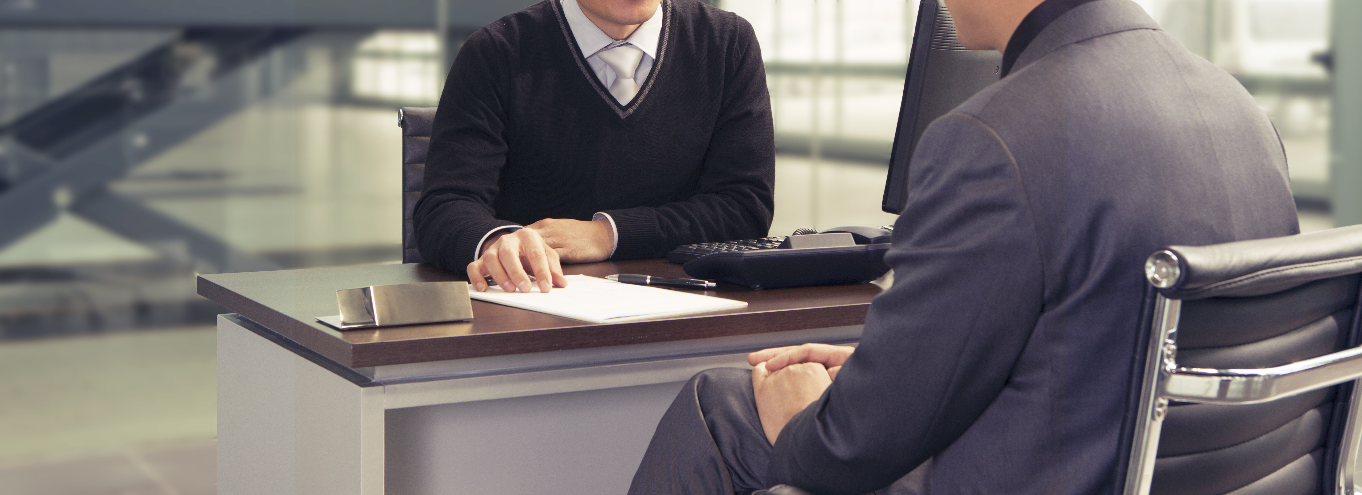 shutterstock_535943791 (1) man at a dealership looking at a finance contract with a dealer
